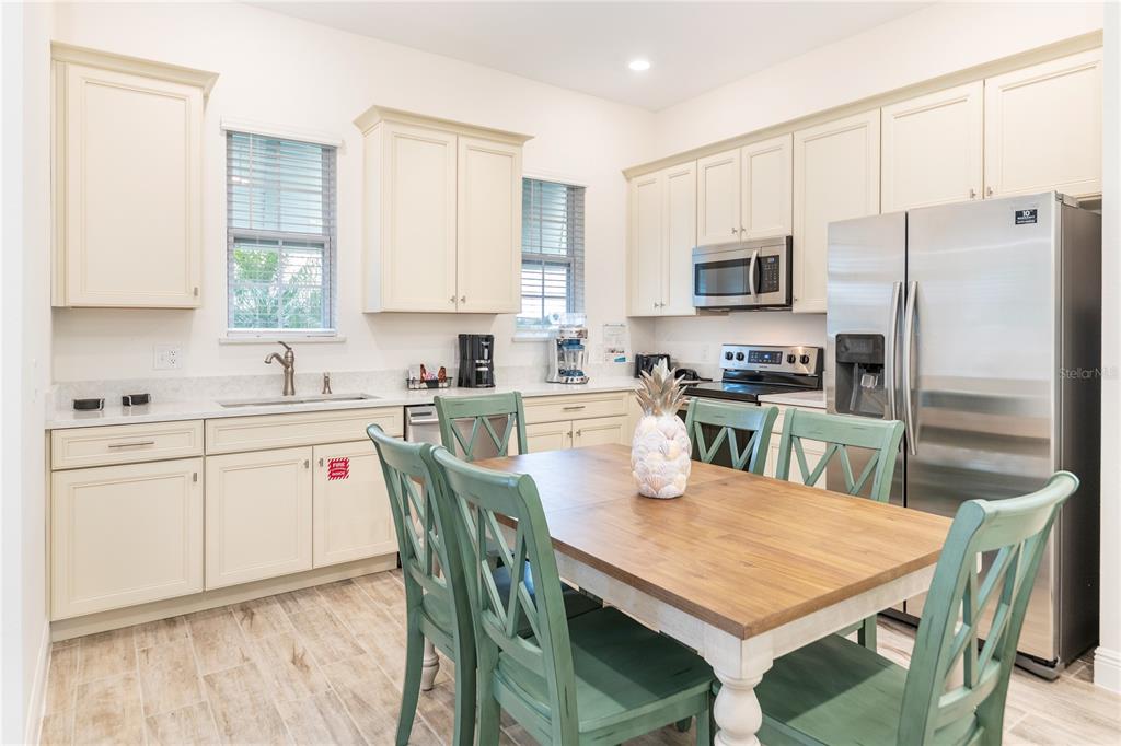 A kitchen with cream cabinets, stainless steel appliances, and a wooden dining table with chairs — 2988 SALTED RIM ROAD, KISSIMMEE, FL