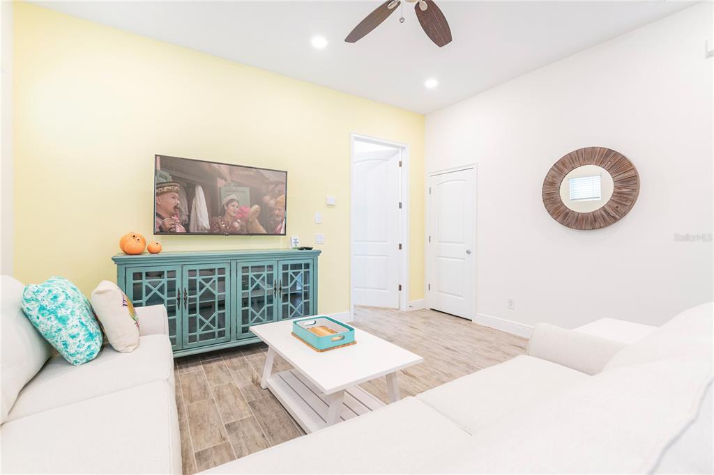 A living room features a light yellow accent wall, a teal media console, and white sofas — 2988 SALTED RIM ROAD, KISSIMMEE, FL