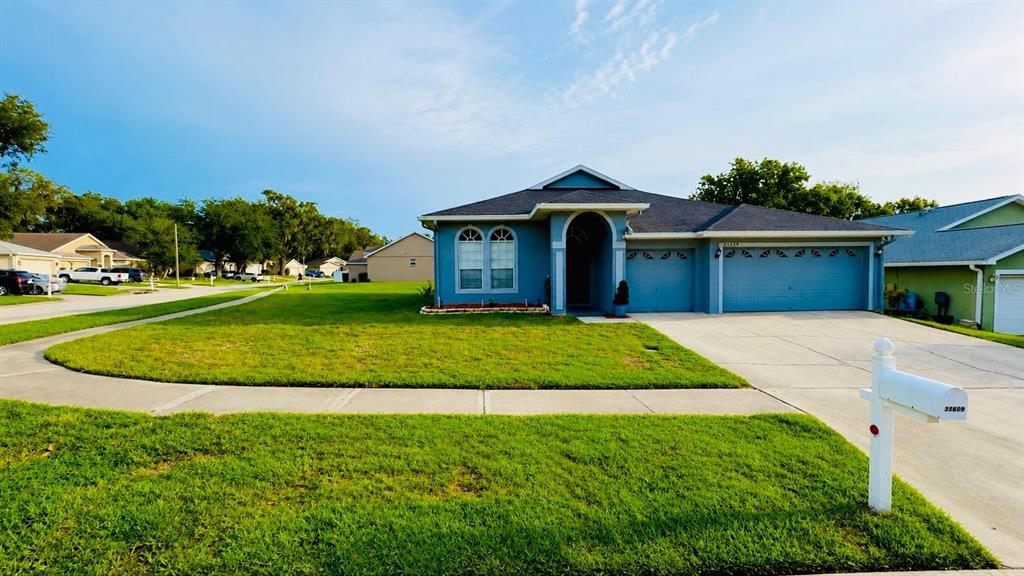A single-story suburban house with a blue exterior, a two-car garage, and a front lawn — 35609 WELBY COURT, ZEPHYRHILLS, FL