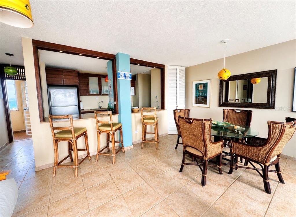 A dining area and kitchen breakfast bar feature wicker furniture and tile flooring — Ocean Drive PLAYA AZUL UNIT 90, LUQUILLO, PR