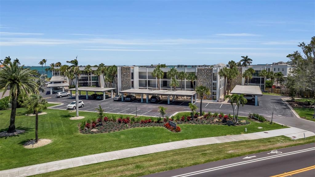An aerial view of a multi-story apartment building with covered parking and landscaped grounds — 448 GULF OF MEXICO DRIVE UNIT A205, LONGBOAT KEY, FL