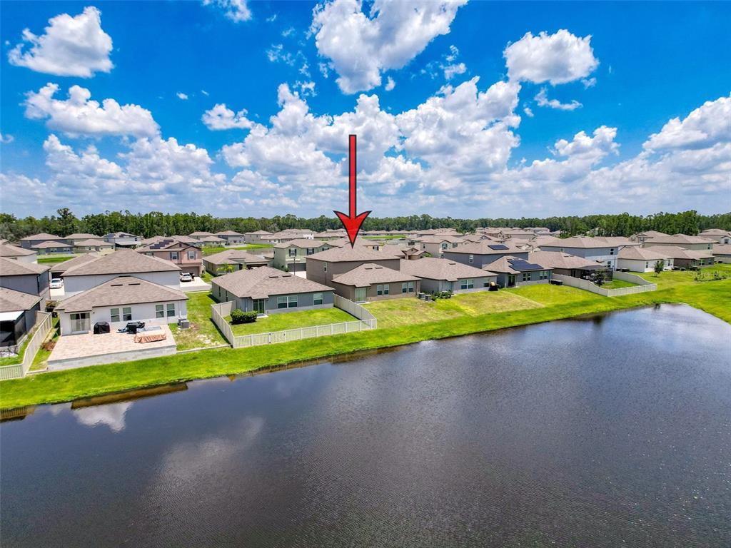 An aerial view shows a two-story suburban house with a fenced backyard facing a pond — 4395 TROTTERS WAY, LAKELAND, FL