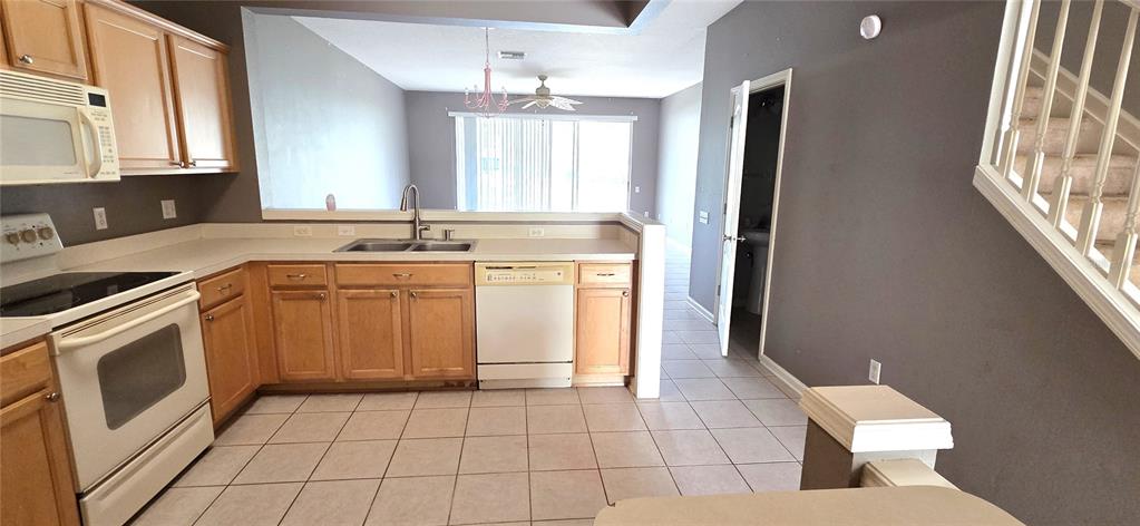 A kitchen with light wood cabinets, white appliances, and tile flooring opens to a living area — 2729 CONCH HOLLOW DRIVE, BRANDON, FL