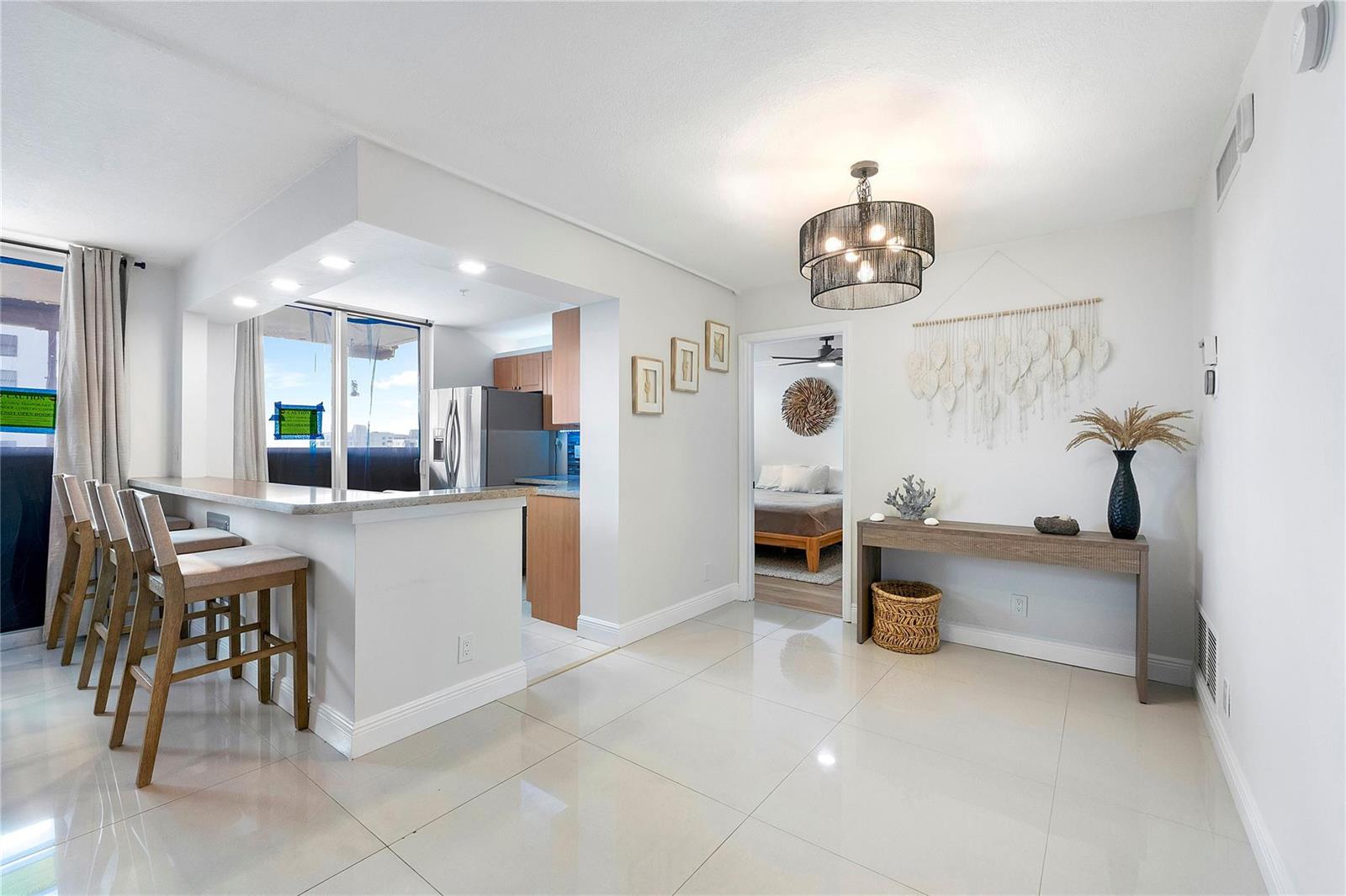 A kitchen with a breakfast bar, dining area, and entryway leading to a bedroom — 1505 N Riverside Drive # 1003, Pompano Beach FL 33062, POMPANO BEACH, FL