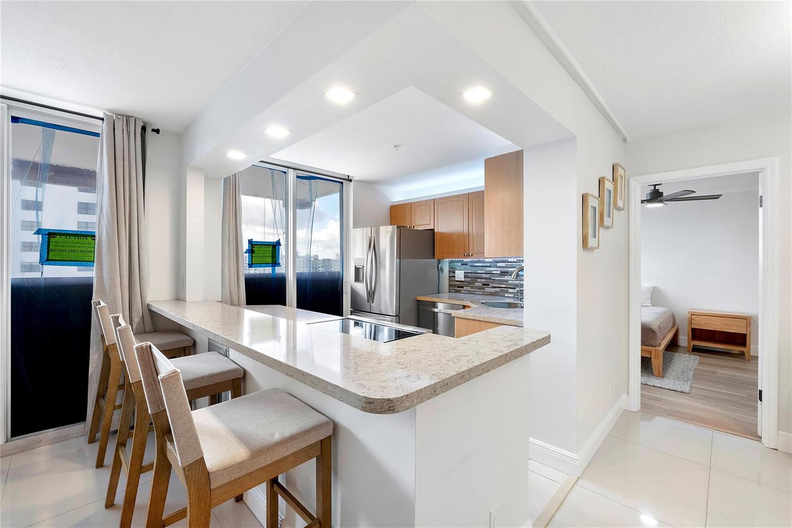 A kitchen with light wood cabinets and a stone breakfast bar overlooks a balcony — 1505 N Riverside Drive # 1003, Pompano Beach FL 33062, POMPANO BEACH, FL
