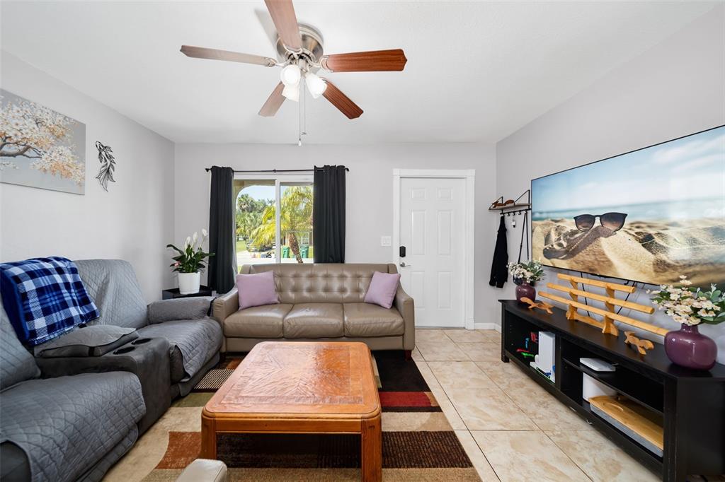 A living room features a leather sofa, a wooden coffee table, and a large television — 2500 LINTON LANE, PORT CHARLOTTE, FL