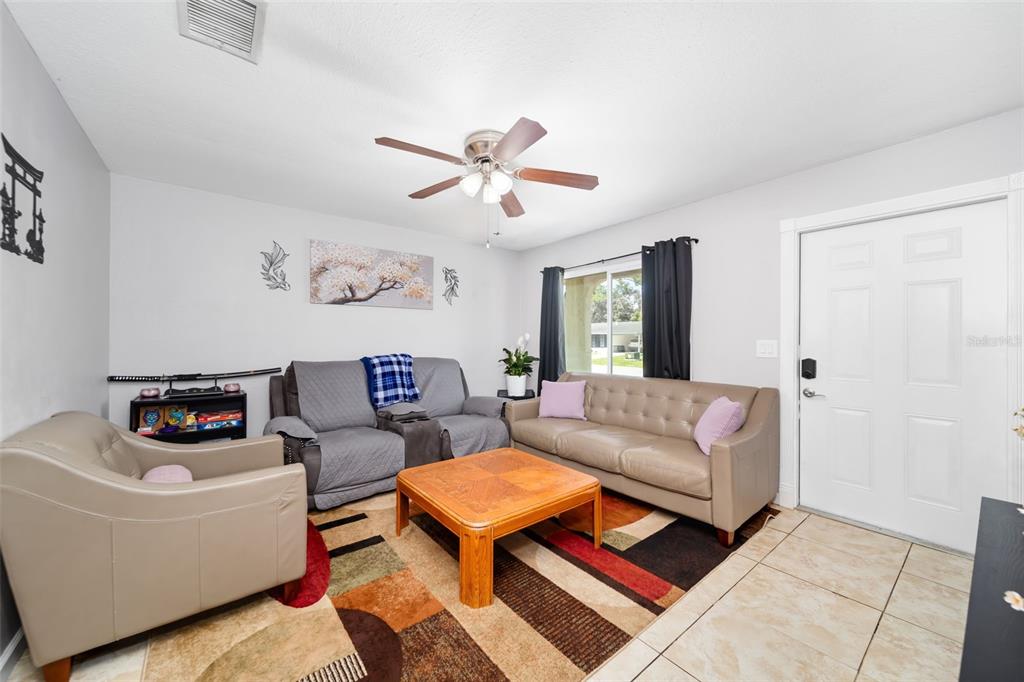 A living room features tile flooring, a patterned area rug, and three pieces of furniture — 2500 LINTON LANE, PORT CHARLOTTE, FL