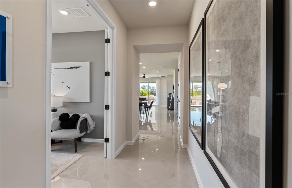 A hallway with light tile flooring leads toward a dining area with a view outside — 8953 BLISSFUL BREEZE TRAIL, MELBOURNE, FL