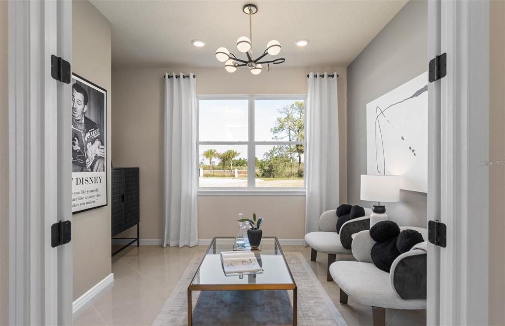 A bright sitting room features two curved chairs, a glass coffee table, and a chandelier — 8953 BLISSFUL BREEZE TRAIL, MELBOURNE, FL