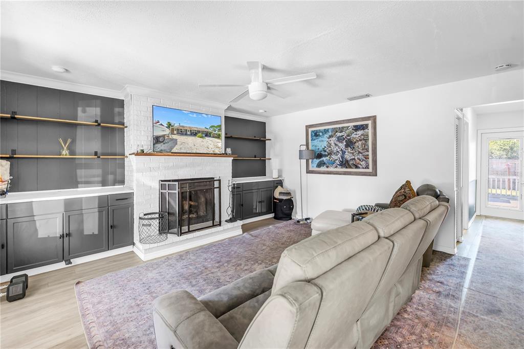 A living room features a white brick fireplace, dark gray built-in cabinetry, and a gray sofa — 4078 GROVELAND AVENUE, SARASOTA, FL