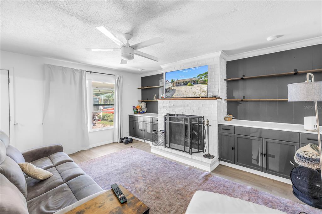 A living room features a white brick fireplace, dark gray built-in cabinets, and shelving — 4078 GROVELAND AVENUE, SARASOTA, FL