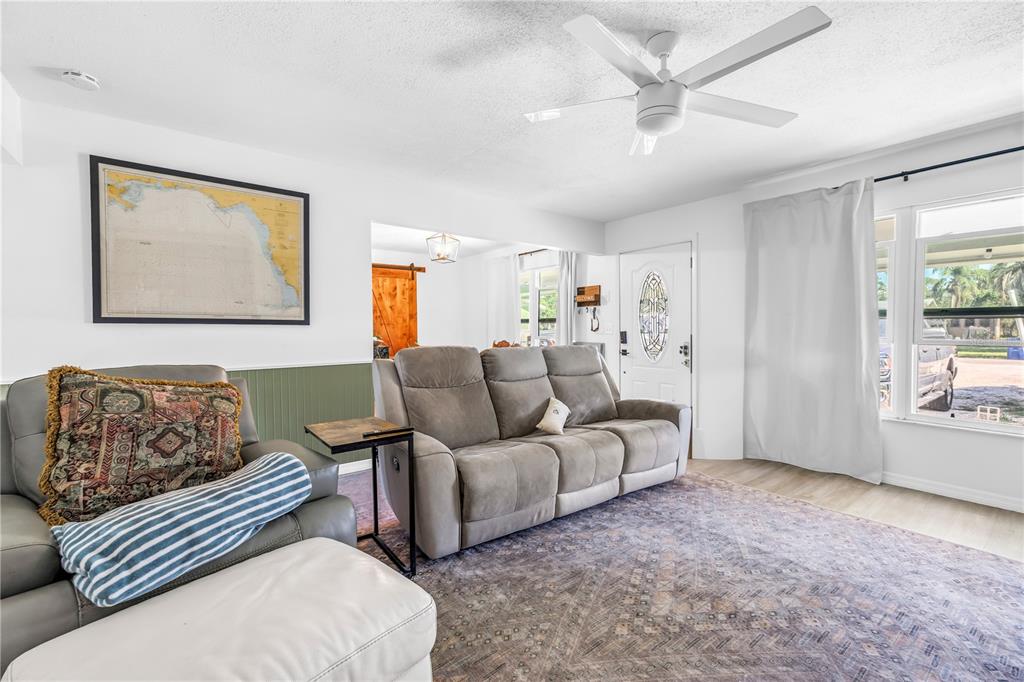 A living room features a gray sofa, a patterned rug, and a framed map — 4078 GROVELAND AVENUE, SARASOTA, FL