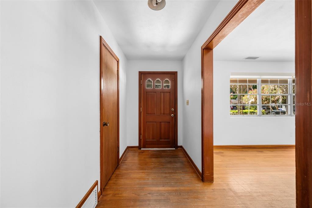 A wooden front door opens into a foyer with hardwood floors and white walls — 3716 SW 6TH PLACE, GAINESVILLE, FL