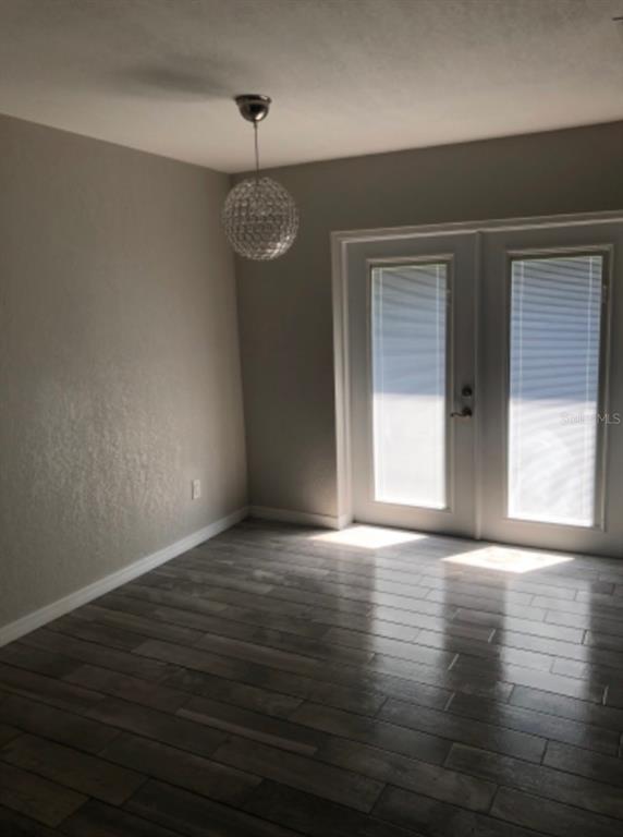 A dining area with wood-look tile flooring, a crystal pendant light, and glass-paned double doors — 2115 DARDANELLE DRIVE, ORLANDO, FL