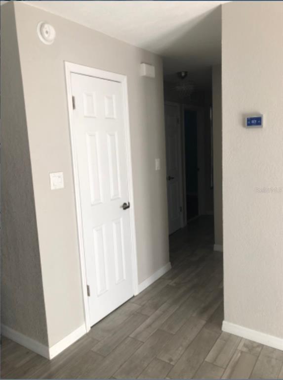 A hallway with light wood-look flooring, a white door, and a wall-mounted thermostat — 2115 DARDANELLE DRIVE, ORLANDO, FL