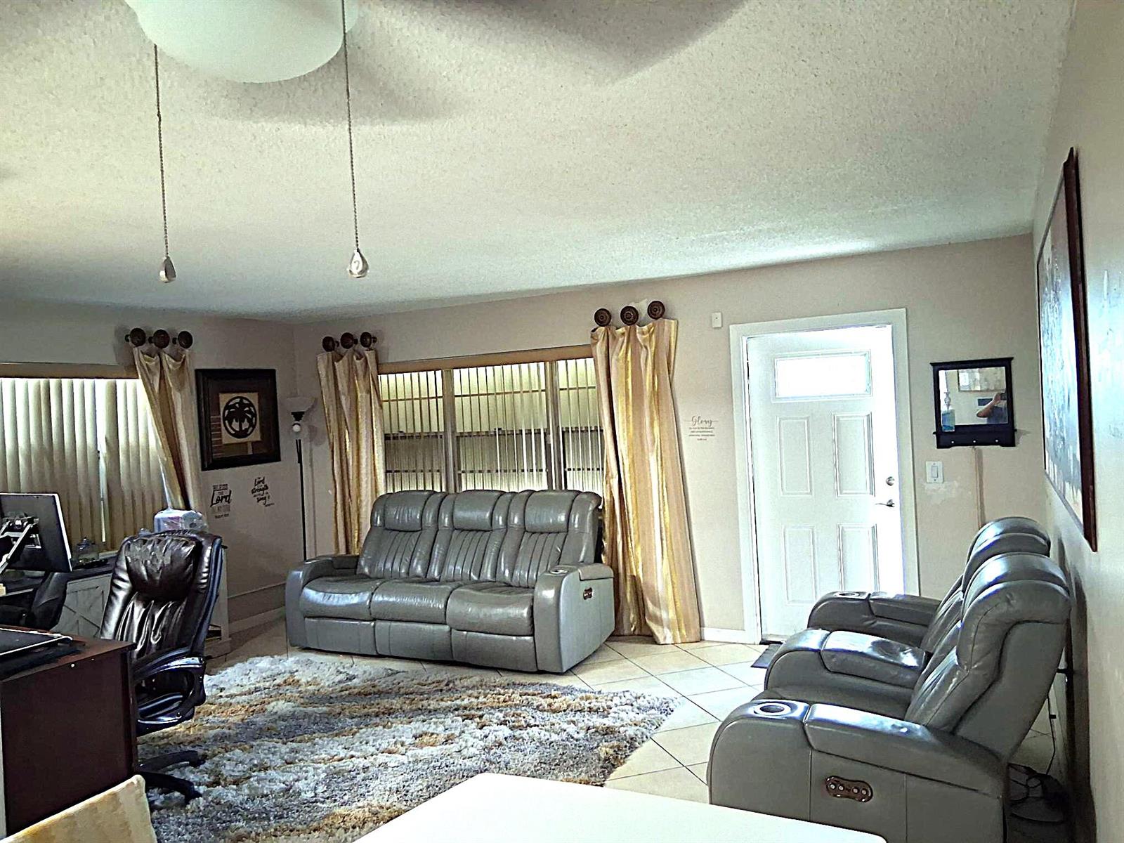 A living room features gray reclining sofas, a textured area rug, and a front door — 6 Northampton # A, West Palm Beach FL 33417, WEST PALM BEACH, FL