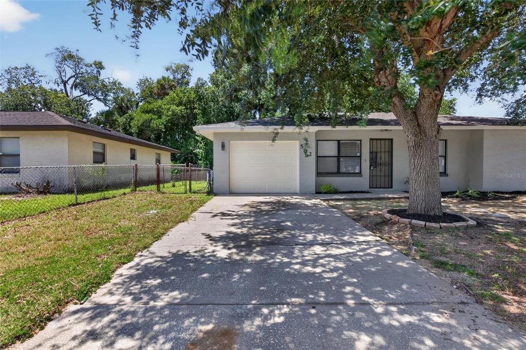 A single-story house with a concrete driveway, a one-car garage, and a large shade tree — 502 LOOMIS TRAIL, DAYTONA BEACH, FL