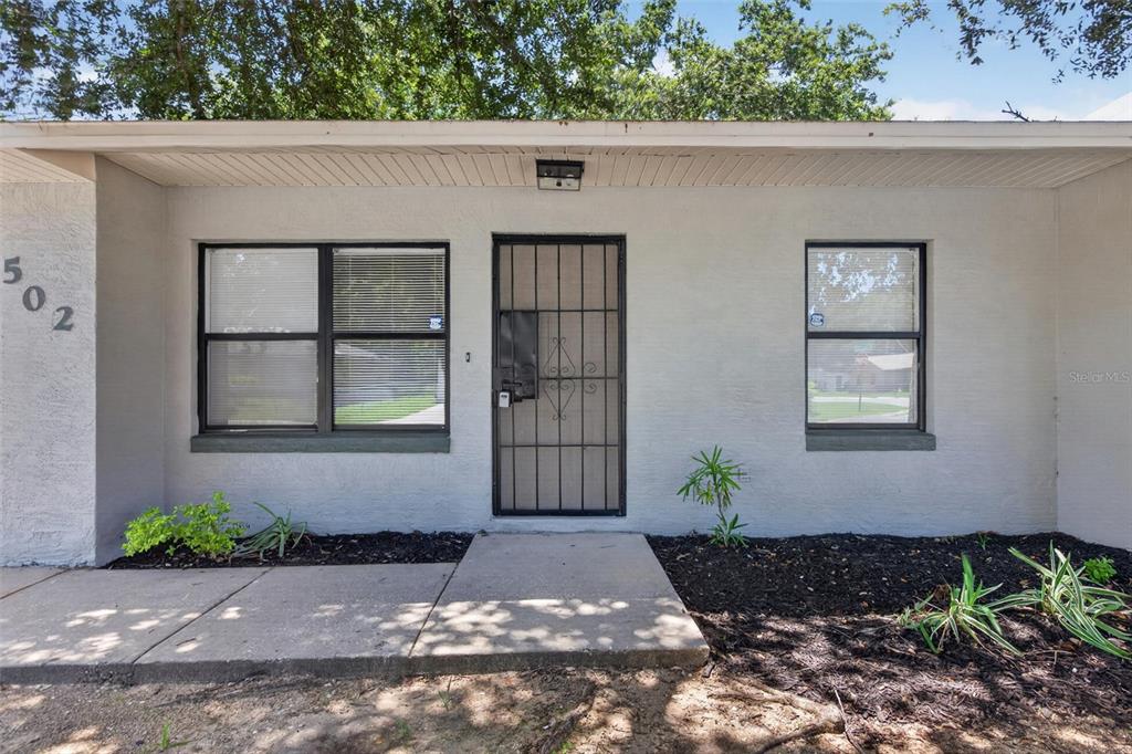 The exterior of a single-story house features a front door with a security gate — 502 LOOMIS TRAIL, DAYTONA BEACH, FL