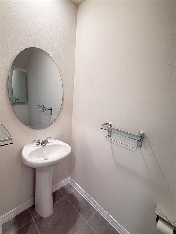 A powder room features a pedestal sink, an oval mirror, and a glass wall shelf — 3164 GOOSE ROAD, DAVENPORT, FL