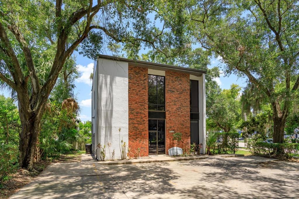 A two-story commercial building with a brick facade and white stucco sides sits among trees — 200 N THORNTON AVENUE, ORLANDO, FL