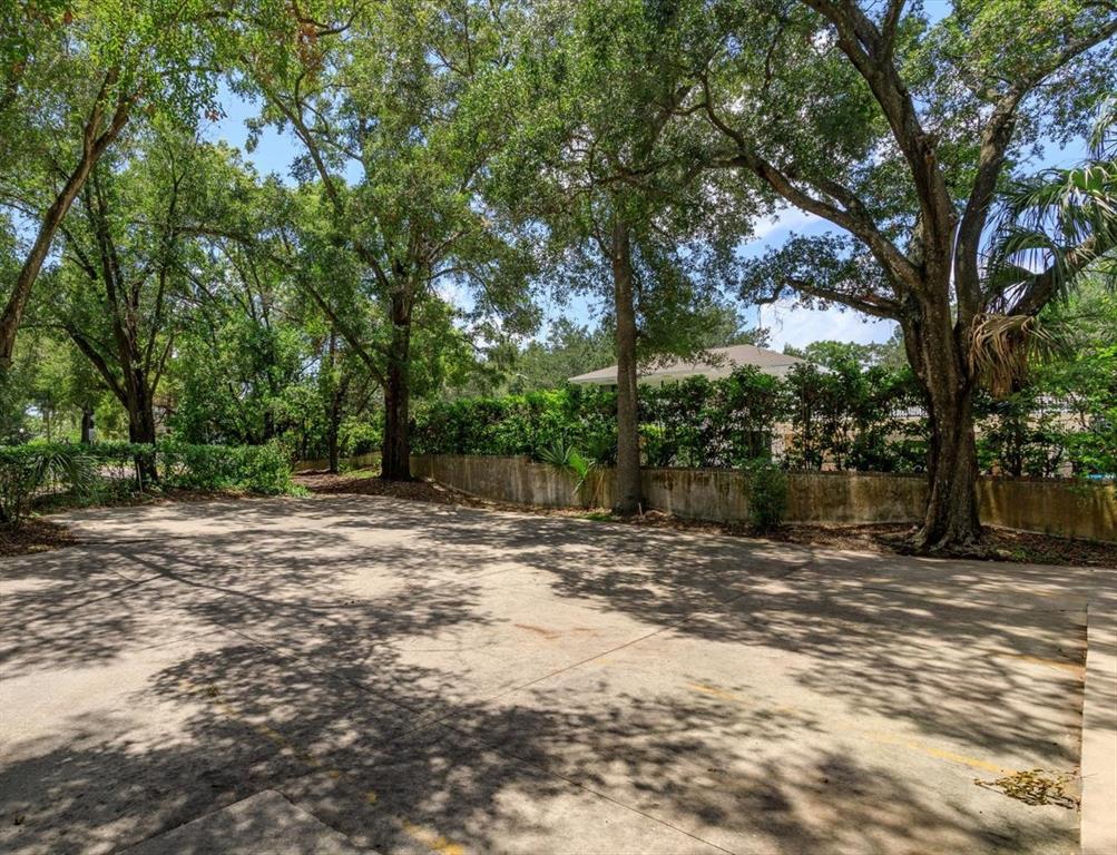 A paved parking area is surrounded by mature trees and a low concrete retaining wall — 200 N THORNTON AVENUE, ORLANDO, FL