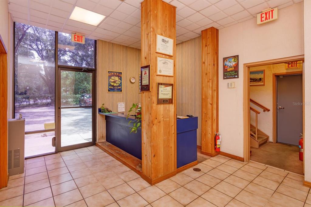 A lobby area features a reception desk, wood-paneled columns, tiled flooring, and multiple exit signs — 200 N THORNTON AVENUE, ORLANDO, FL