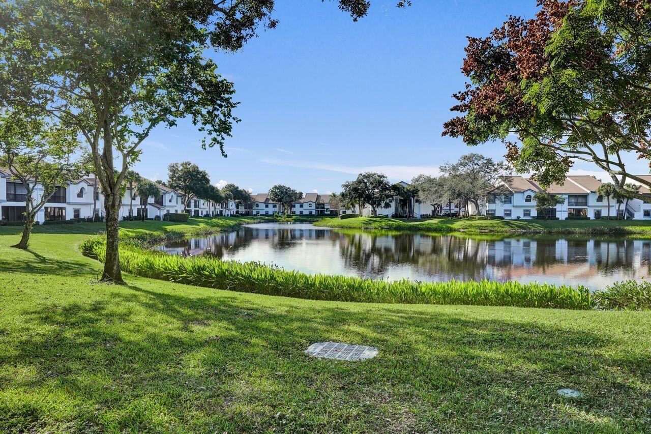 A grassy lawn leads to a pond surrounded by multi-story residential buildings and trees — 5415 Verona Drive # I, Boynton Beach FL 33437, BOYNTON BEACH, FL