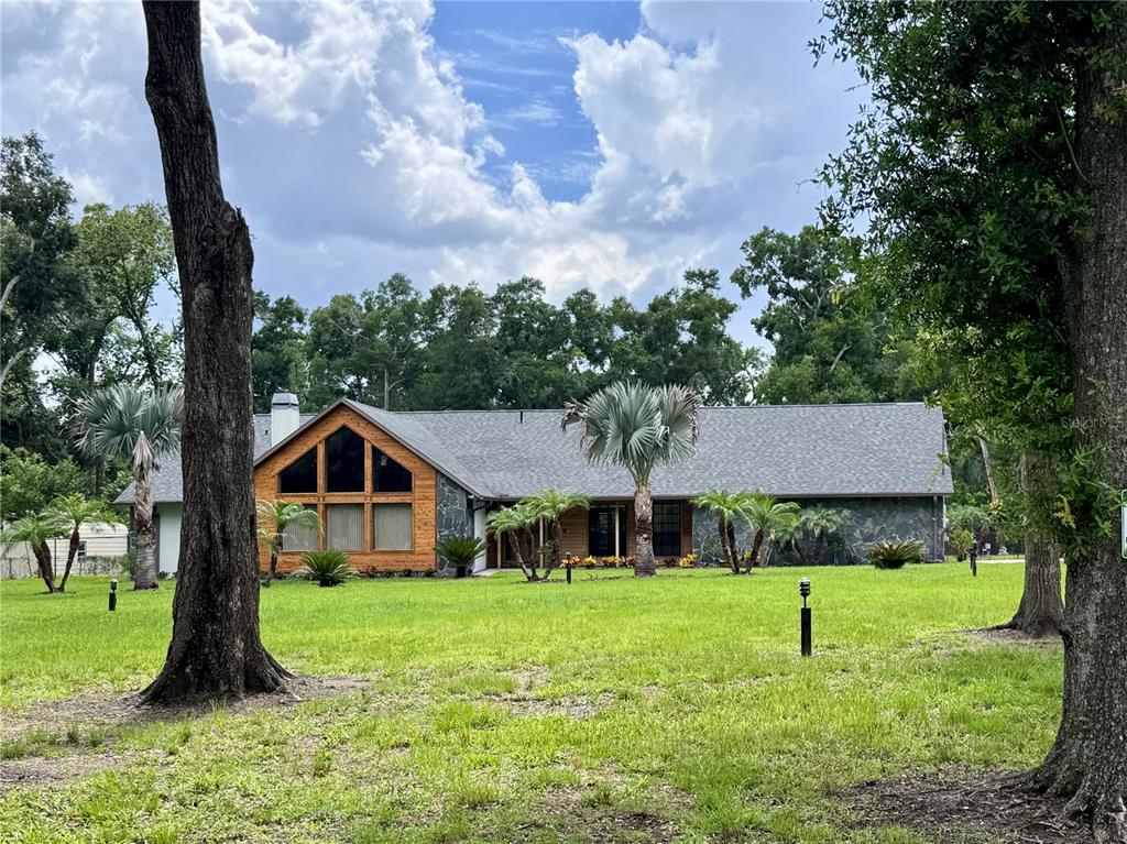 A single-story house with stone siding and a large triangular window sits on a lawn — 3415 RANCH ROAD, VALRICO, FL