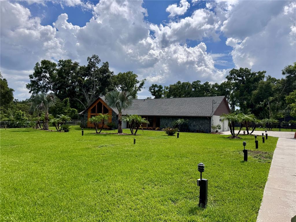 A single-story house with a stone facade and a large lawn under a cloudy sky — 3415 RANCH ROAD, VALRICO, FL