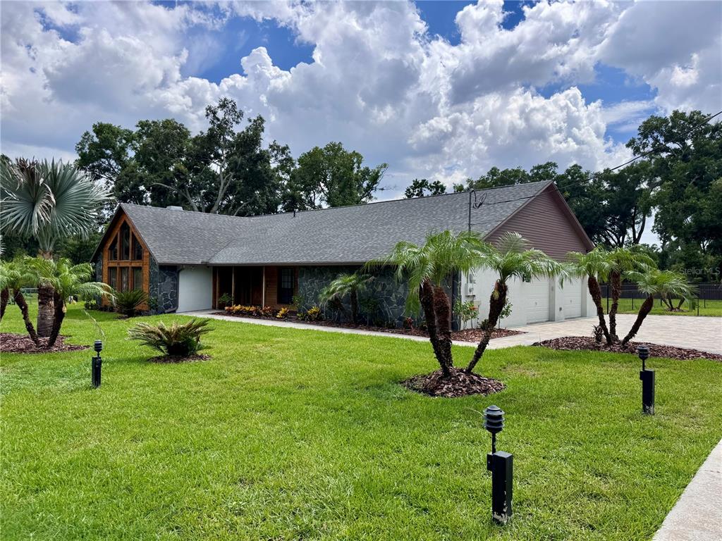A single-story house with stone siding, a gray shingled roof, and palm trees in front — 3415 RANCH ROAD, VALRICO, FL