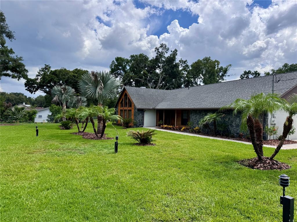 A single-story house with a stone facade and a large triangular window sits on grass — 3415 RANCH ROAD, VALRICO, FL