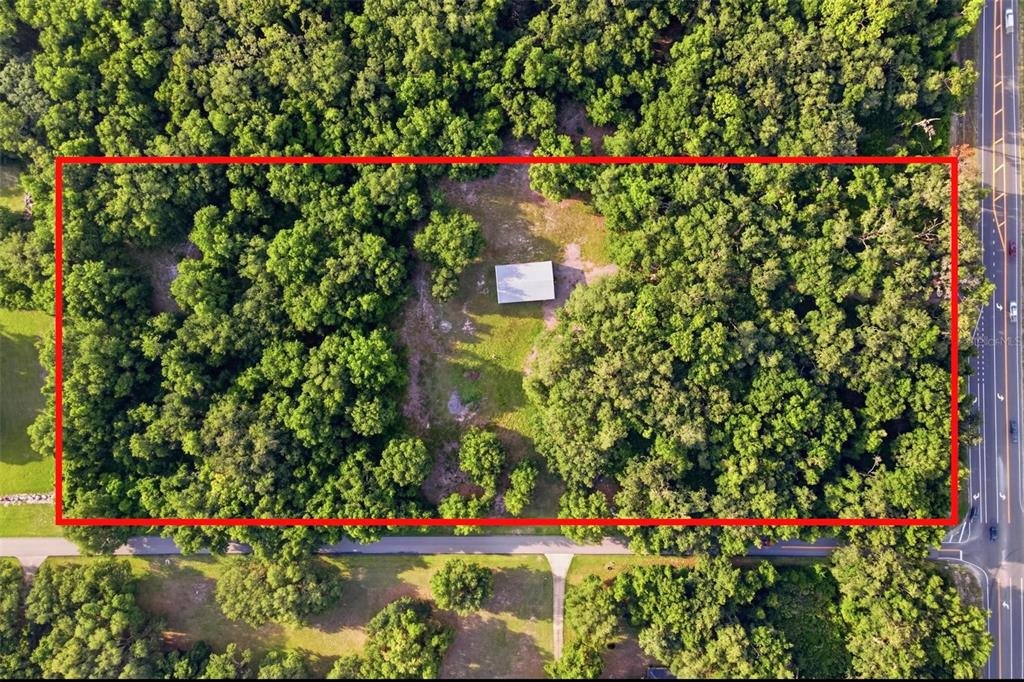 An aerial view shows a rectangular lot with dense trees and a single detached structure — 7112 MARSH BEND TRAIL, WILDWOOD, FL