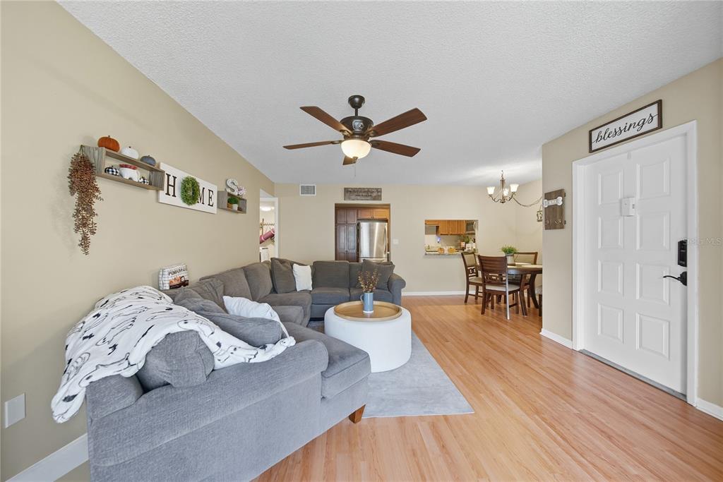 A living room with a gray sectional sofa, a white ottoman, and a dining area — 3100 LAKE PINE WAY UNIT A2, TARPON SPRINGS, FL