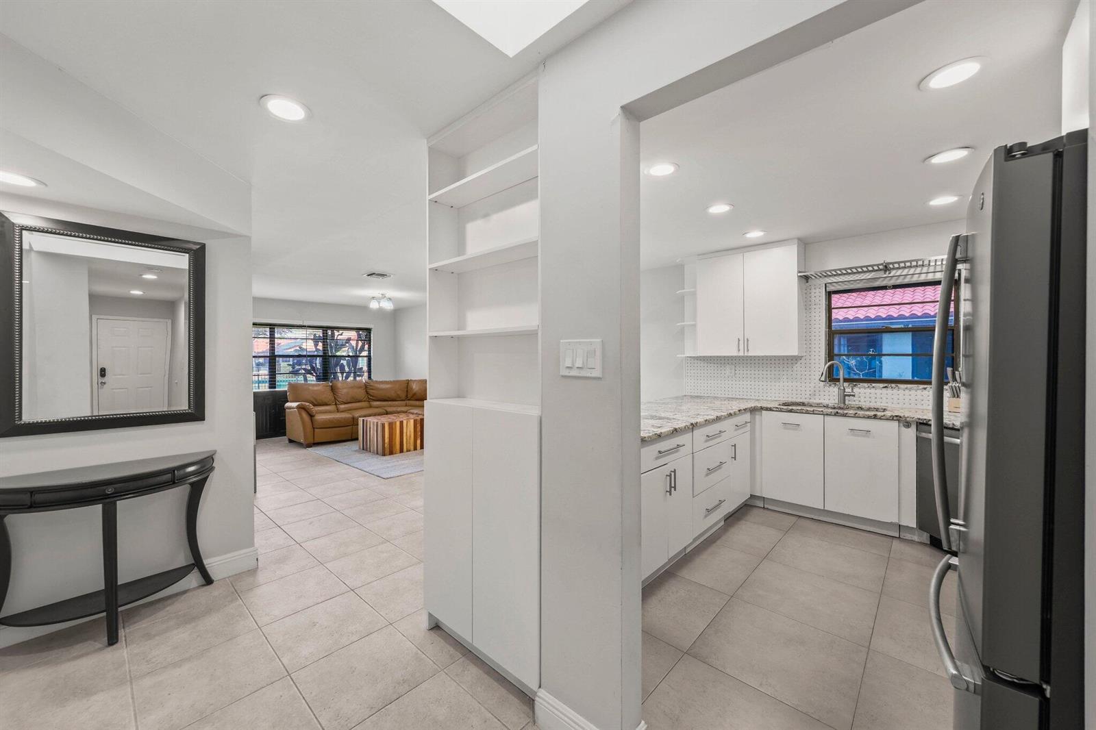 A view from a tiled entryway into a white kitchen and a living room beyond — 41 Bethesda Park Circle # K41, Boynton Beach FL 33435, BOYNTON BEACH, FL