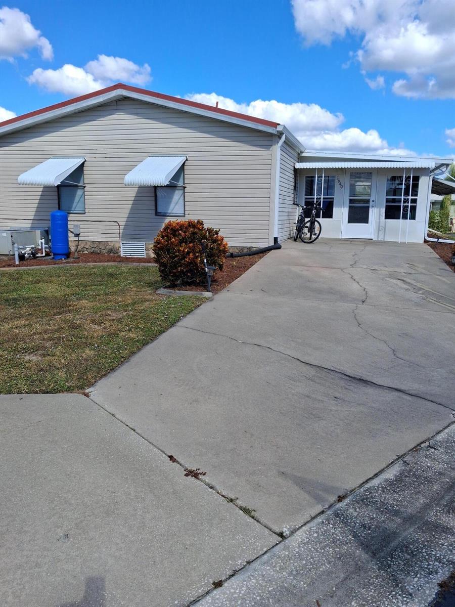 A single-story house with light siding, a concrete driveway, and a blue water tank — 1640 SW 35th Circle, Okeechobee FL 34974, OKEECHOBEE, FL
