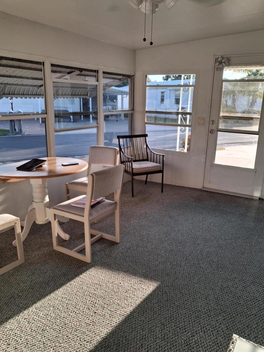 A sunroom features a round table with chairs, carpeted flooring, and large windows — 1640 SW 35th Circle, Okeechobee FL 34974, OKEECHOBEE, FL