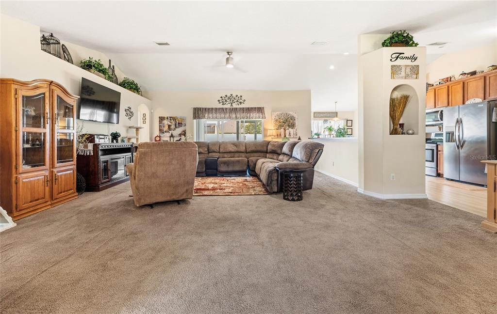 A living room features a sectional sofa, a recliner, and an open-concept kitchen area — 33 ROYAL LEAF LANE, PALM COAST, FL