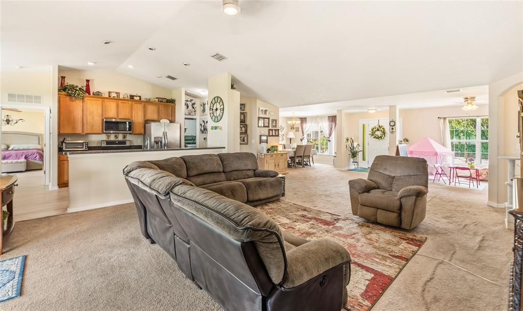 An open-concept living room features a kitchen with wood cabinets and a carpeted floor — 33 ROYAL LEAF LANE, PALM COAST, FL