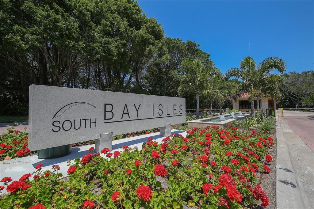 A stone sign for South Bay Isles sits in front of red flowers and trees — 1930 HARBOURSIDE DRIVE UNIT 134, LONGBOAT KEY, FL
