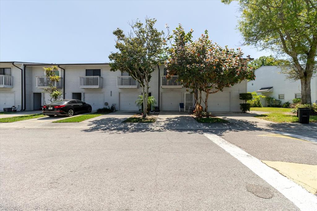 A row of two-story townhomes with attached garages and balconies under a clear blue sky — 6420 92ND PLACE UNIT 1202, PINELLAS PARK, FL