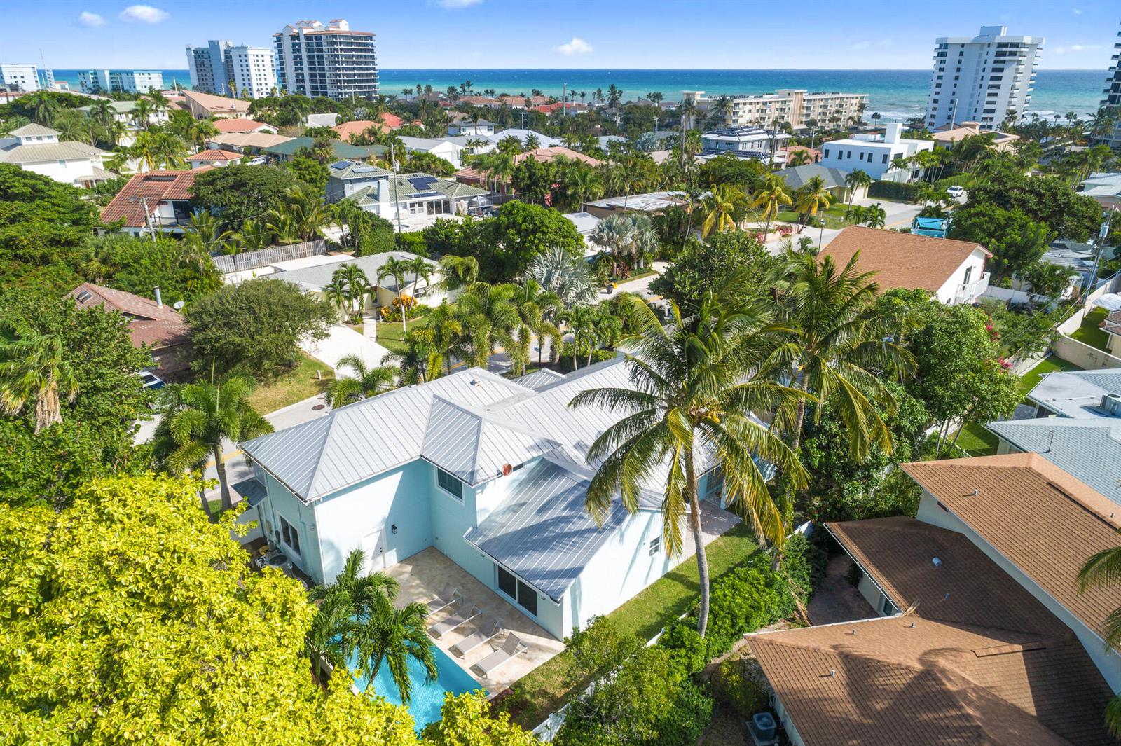 An aerial view of a light blue house with a metal roof and backyard pool — 490 Mars Way, Juno Beach FL 33408, JUNO BEACH, FL