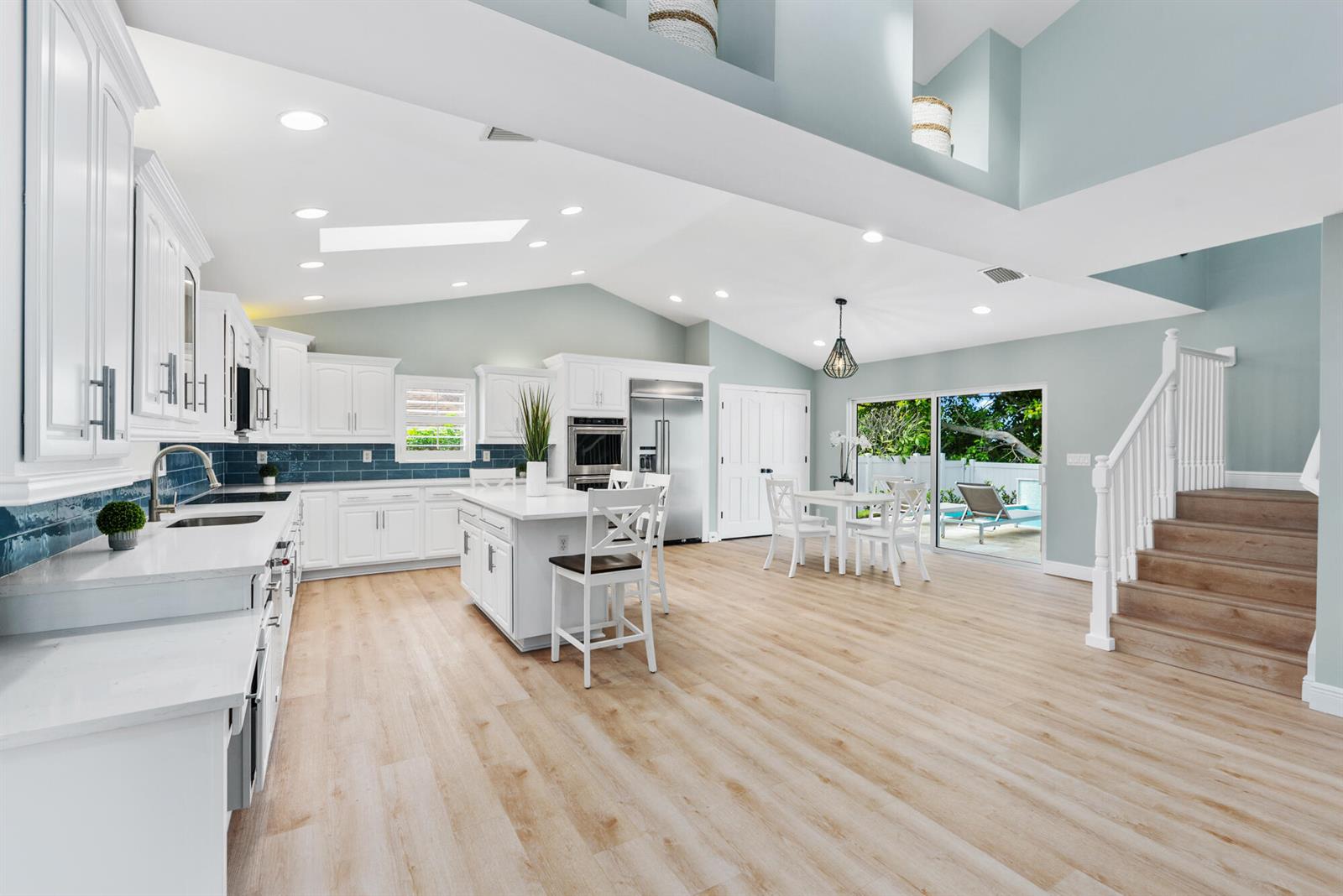 A bright kitchen features white cabinetry, a center island, and stairs leading to an upper level — 490 Mars Way, Juno Beach FL 33408, JUNO BEACH, FL