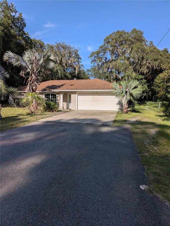 A single-story house with a two-car garage, asphalt driveway, and palm trees in the front yard — 2203 MARSH ROAD, DELAND, FL