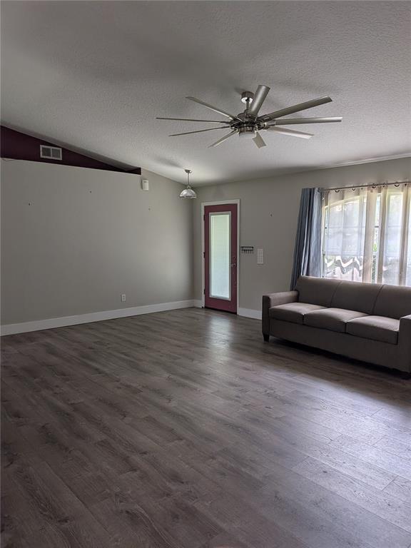 A living room features gray wood-look flooring, a ceiling fan, and a sofa near windows — 2203 MARSH ROAD, DELAND, FL
