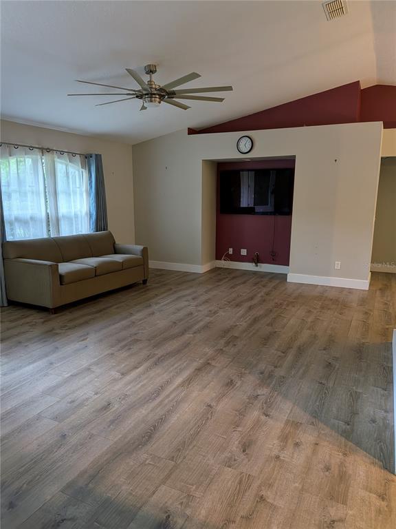 A living room features wood-look flooring, a ceiling fan, and a recessed television wall — 2203 MARSH ROAD, DELAND, FL