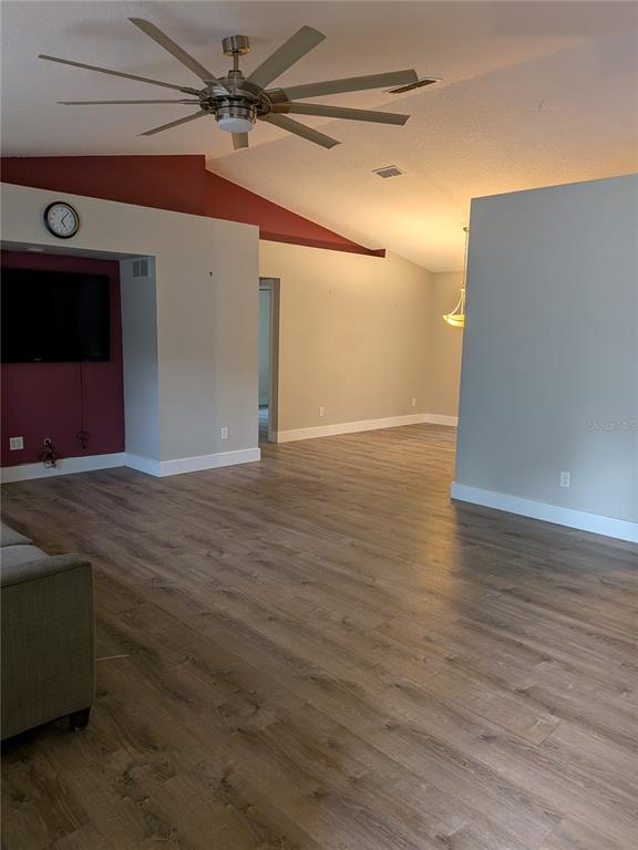A living room features wood-look flooring, a vaulted ceiling with a fan, and a red accent wall — 2203 MARSH ROAD, DELAND, FL