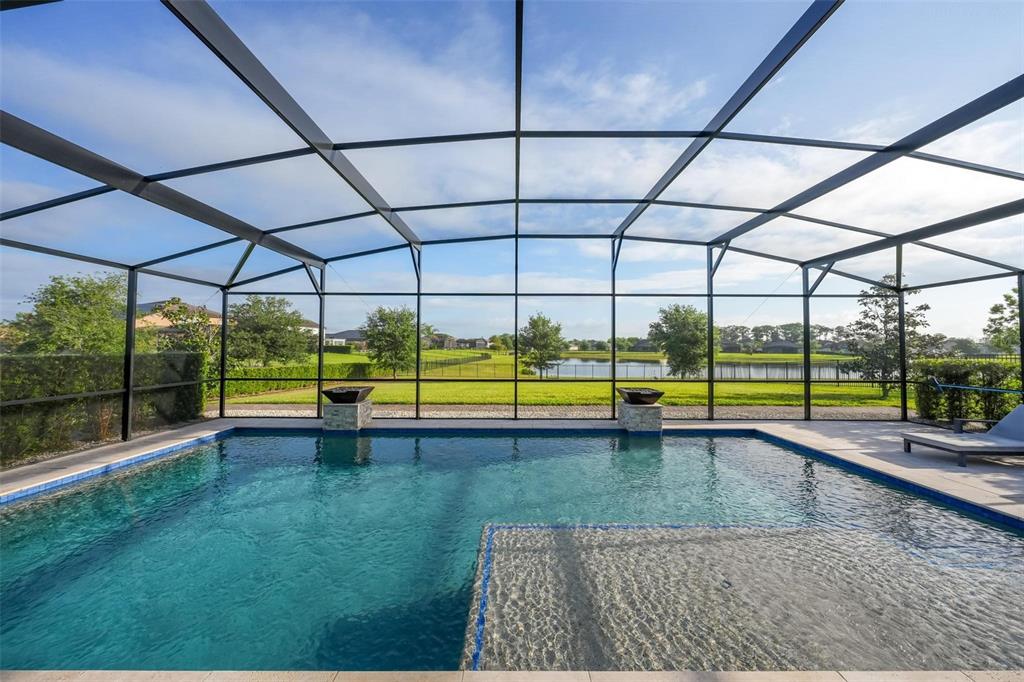 A screened-in swimming pool overlooks a grassy lawn and a pond under a blue sky — 17507 LAGODA LANE, ORLANDO, FL