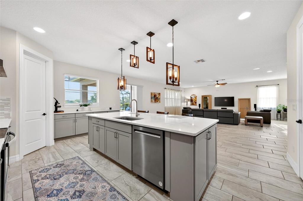 A kitchen with a grey island and stainless steel appliances opens into a living room — 17507 LAGODA LANE, ORLANDO, FL