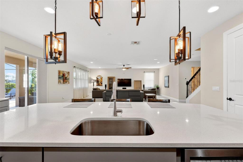 A kitchen island with a stainless steel sink overlooks an open-concept living room — 17507 LAGODA LANE, ORLANDO, FL