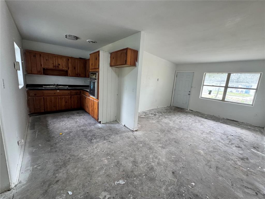 A kitchen with wood cabinets and a living area with an unfinished concrete floor — 517 MOROCCO AVENUE, ORLANDO, FL